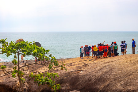 A group of Asian tourists with a guide sightseeing on the seashore on the island of Koh Samui, Thailand - 05.03.2022のeditorial素材
