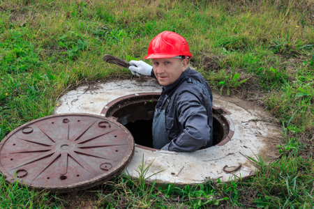 A male plumber in a helmet descended into an open water well for inspection and repair.の写真素材