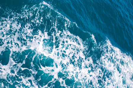 Blue sea water with waves and foam, top view. water surface, background.