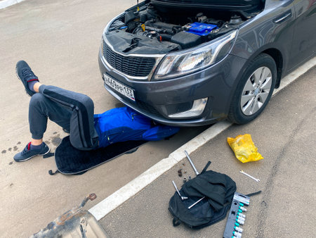 a man lies under the car and fixes the breakdown. The problem is on the road. Russia, Anapa-21.04.22のeditorial素材