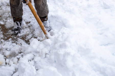 A man removes snow with a shovel on a winter day after a heavy snowfall.の写真素材