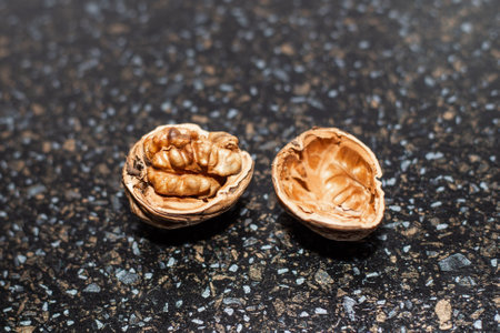 A ripe open walnut in its shell on a black table.