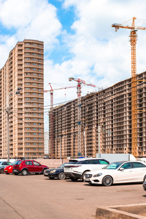 Construction site with cranes and high-rise buildings in the city. Nearby parking with cars. Krasnodar, Russia-28.04.2022のeditorial素材