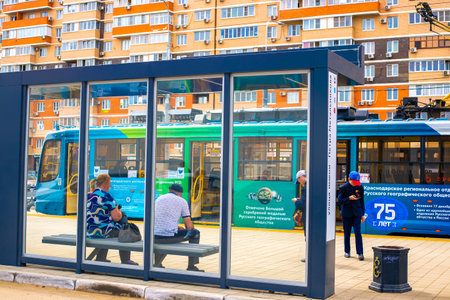 People waiting for a streetcar at a transparent streetcar stop in Krasnodar, Russia-28.04.2022のeditorial素材