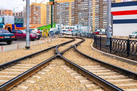 Streetcar tracks converging in a single line on a city street with houses and traffic. Krasnodar, Russia-28.04.2022のeditorial素材