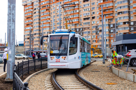 The streetcar is running on a new streetcar line in the city, with workers completing the guardrails. Russia, Krasnodar-28.04.2022 .municipal transport-transferのeditorial素材