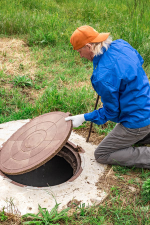 the man opened the cover of the sewer manhole to pump out the sewage.の写真素材
