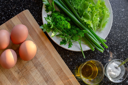 Boiled chicken eggs and fresh greens on the table for preparing spring fresh salad.の写真素材