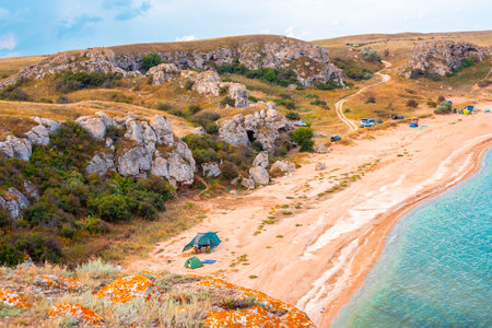 Tourist tent camp on the seashore in a bay between rocky hills. Travel and tourism.の写真素材