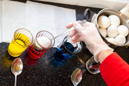 A woman dyes chicken eggs in multi-colored food dyes. Preparing for the feast of the holy Easter.の写真素材