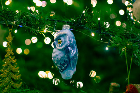 Christmas toy owl on a Christmas tree with blurred sides from the lights. Celebrating the New Year and Christmas.の写真素材