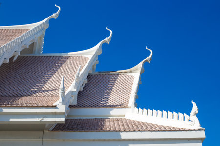 roof with decoration of the Buddhist white temple Wat Sawang Arom against the sky.