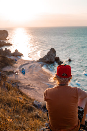 tourist at sunset sits on the top of a mountain and looks at the seascape. Travel and tourism.の写真素材