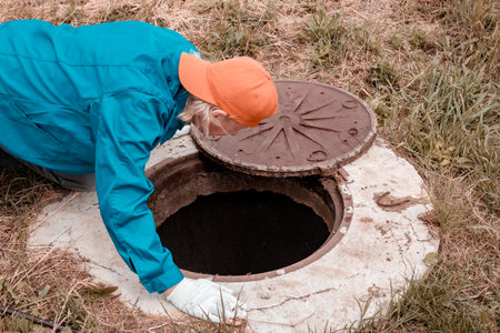 The worker leaned over the well. Plumbing work in rural areas.の写真素材