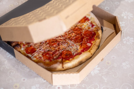 Large pizza cut into pieces in a box on the table. Order food home.の写真素材