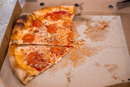 Half-eaten pizza in a cardboard box on the table. Fast food delivery.の写真素材
