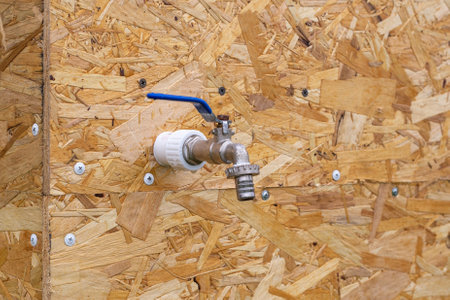 Water tap on a wooden wall surface. Installation of plumbing and water supply in the garden.の写真素材