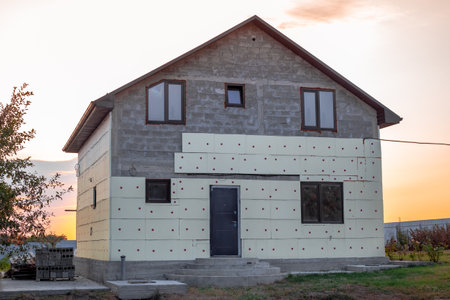 Construction of a two-story house. The stage of exterior finishing and insulation of the walls of a block house using penoplex.の写真素材