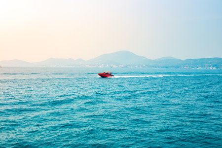 A speedboat sails on the sea in the Gulf of Thailand, illuminated by the sun, view from the water.の写真素材