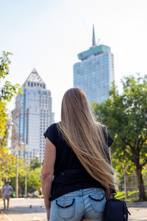 Tourist with long blond hair in a big city looking at skyscrapers, rear view. Travel and tourism.の写真素材