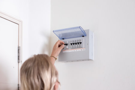 A person turns on a switch on an electrical panel in a room.