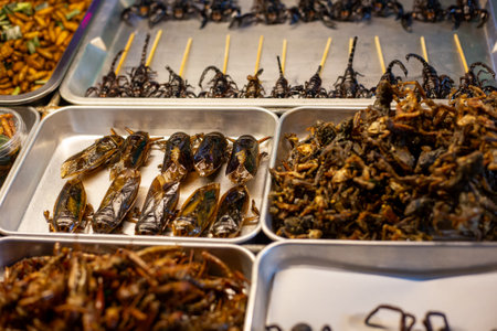 Street food. Dried and fried exotic delicacies of insects and scorpions at a night food market.