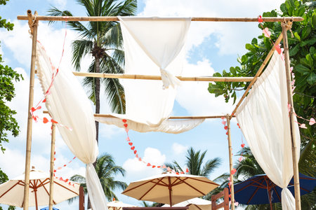 Romantic bamboo gazebo with white canopy decorated with hearts on the shore of a tropical island.の写真素材