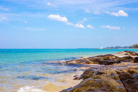 Sea coast with rocky shore and white lighthouse in the distance. Seascape.の写真素材