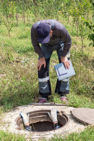 Plumbers repair pipes in a well. A man climbed into the well to inspect and service the water...