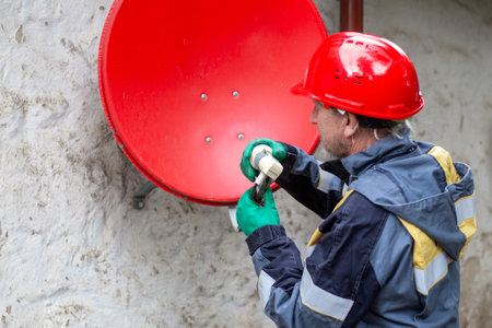 A worker installs a satellite TV antenna to receive a signal. Satellite TV.の写真素材