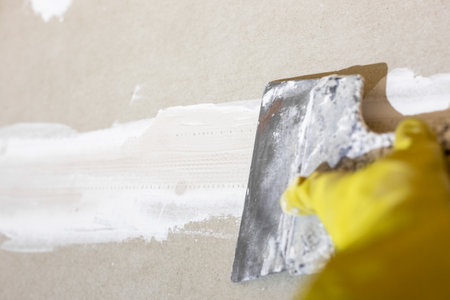 Preparing drywall for plastering. The craftsman cleans and sands the putty from the joints and screws with a spatula.の写真素材