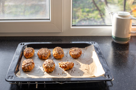 Grain buns with oatmeal, flax, sunflower and sesame seeds on baking paper on a baking sheet. Useful healthy baking.の写真素材