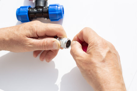 close-up of hands assembling metal threaded part with plastic fittings, winding fumka, sealing tape.