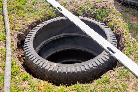A pit for an outdoor village toilet with walls made of rubber tires. Making a toilet on a personal...