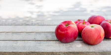 A bunch of bright red apples on a weathered wooden surface with soft lighting and enough space for text.の写真素材