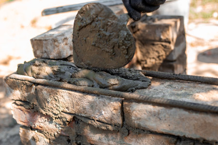 applying wet cement to brick structure showing texture and process of barbecue construction, close-up.の写真素材