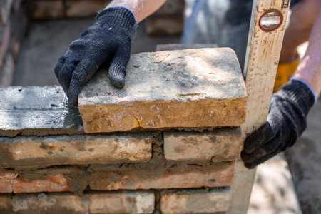 Close-up of leveling bricks during construction of brick structure using spirit level.の写真素材