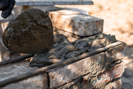 man applying mortar to brick structure with trowel, preparing for further construction.の写真素材