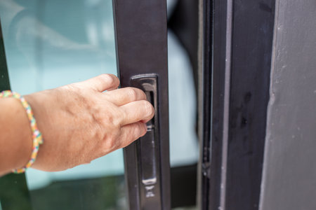 close up of hand sliding modern glass door with black handle.の写真素材