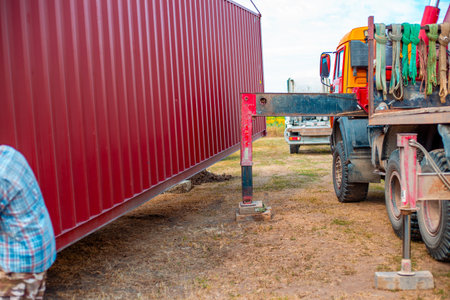 A worker directs a cargo container being lowered into place at its destination.