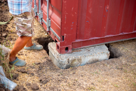 A cargo container is carefully placed on a concrete base.