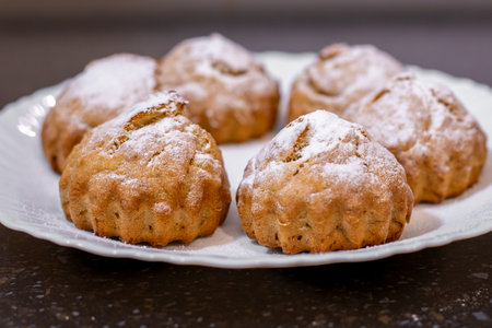 Freshly baked banana muffins elegantly arranged on a white plate, dusted with powdered sugar.