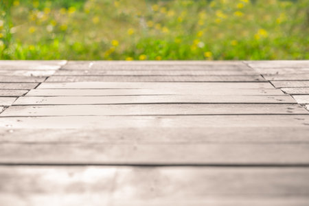 Empty wooden terrace rustic background with blurred field of green grass and yellow flowers in the...