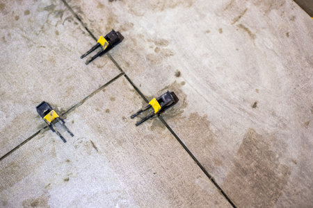 Close-up of tile leveling clips installed between newly laid tiles, the process of setting gaps and...