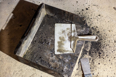 The metal ash pan and scraper are filled with soot and debris that need cleaning. Cleaning and maintaining a fuel boiler.の写真素材