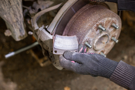 A gloved hand holds a pair of shiny new brake pads ready to be installed into a car's braking system.の写真素材