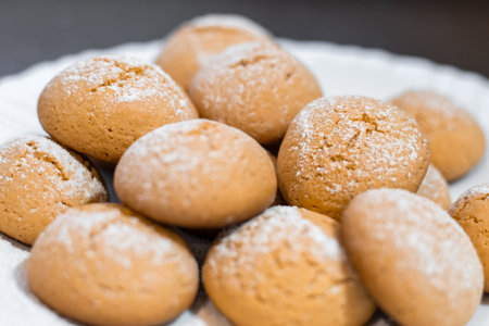 Close-up of homemade cookies dusted with powdered sugar on a white plate, sweet treat.の写真素材