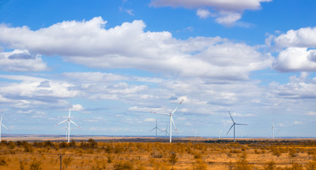Wind turbines rise against a partly cloudy sky, generating renewable energy in a rural area.