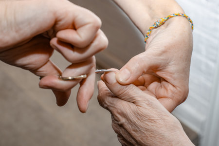 A caregiver trims an elderly woman's nails with nail scissors. Care for the frail elderly.の写真素材