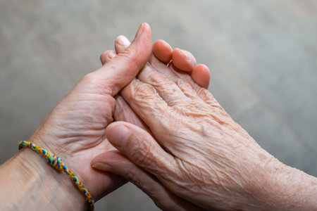 A caregiver holds an elderly womans hands, demonstrating support and connection.の写真素材